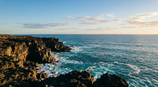 Vue panoramique des falaises de lave noire plongeant dans l'océan turquoise à La Réunion