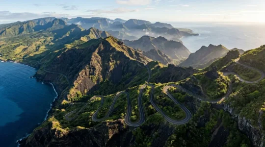 Vue aérienne d'une île volcanique avec routes sinueuses serpentant entre mer turquoise et sommets verdoyants