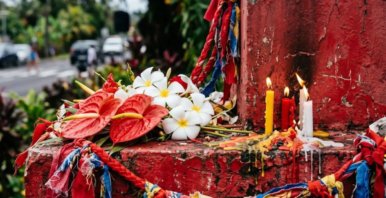 Petit autel rouge de Saint-Expédit à un carrefour de La Réunion, avec des offrandes de fleurs et de bougies.