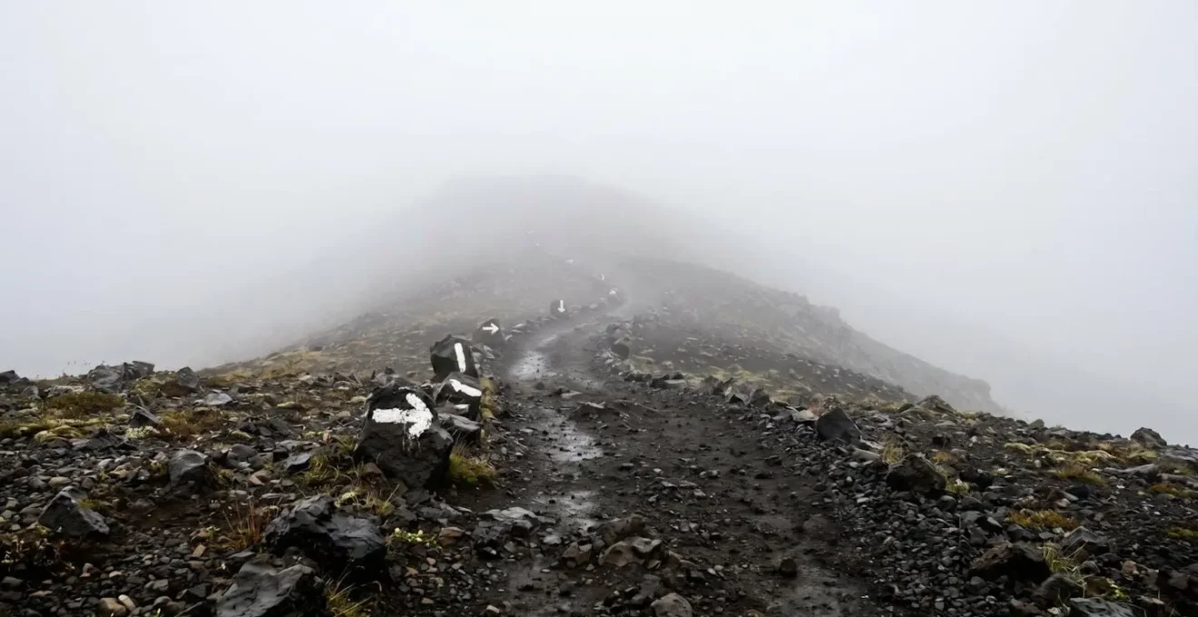 Sentier volcanique avec marques blanches à peine visibles dans le brouillard épais