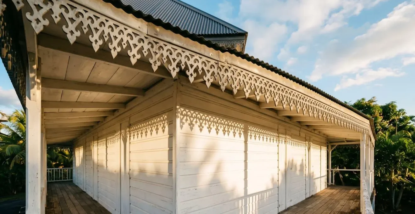 Lambrequin en zinc patiné créant des ombres géométriques sur une façade de case créole